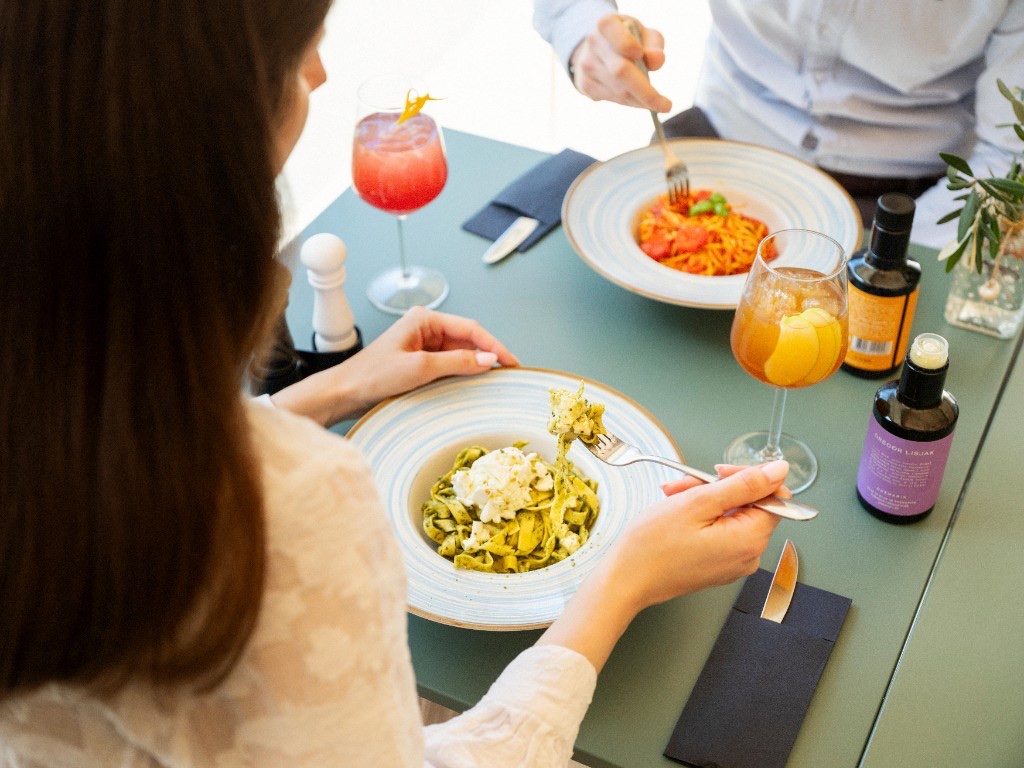 Gosti uživajo v testeninah v pizzeriji Pino
